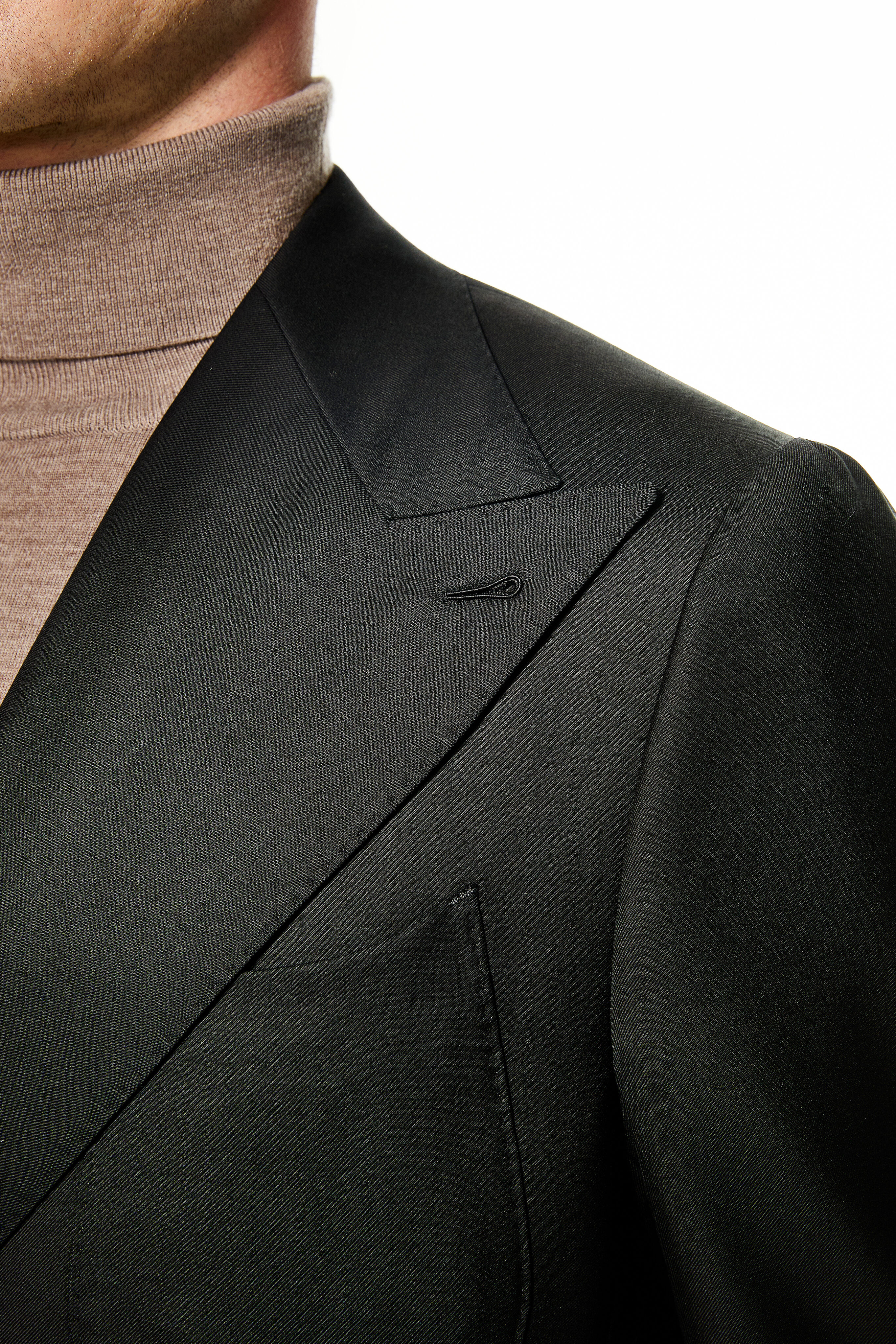 Wide peak lapel with Milanese hand-sewn buttonhole on black 4×2 jacket.