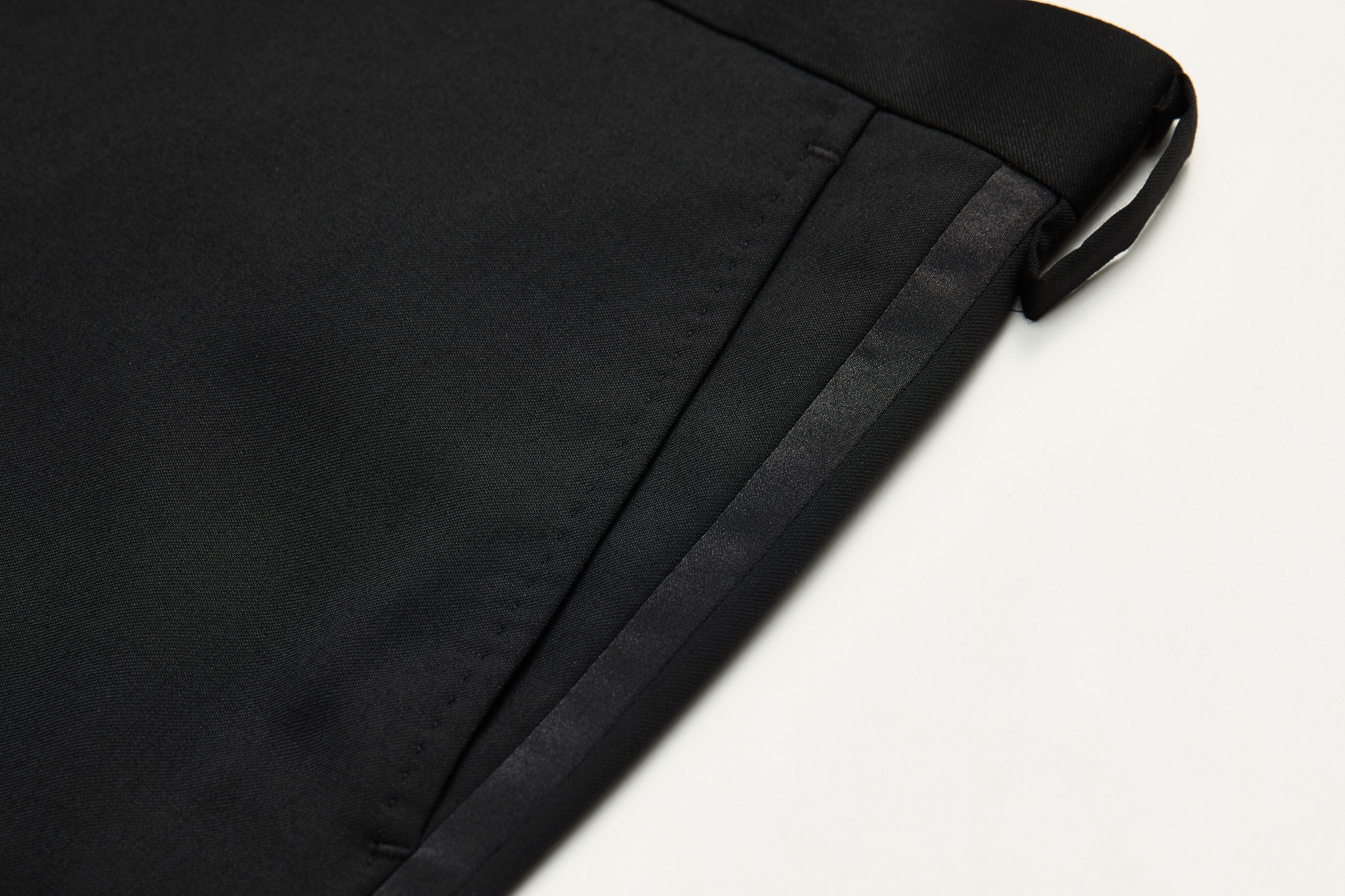 ¼-top pocket detail on black tuxedo trousers.