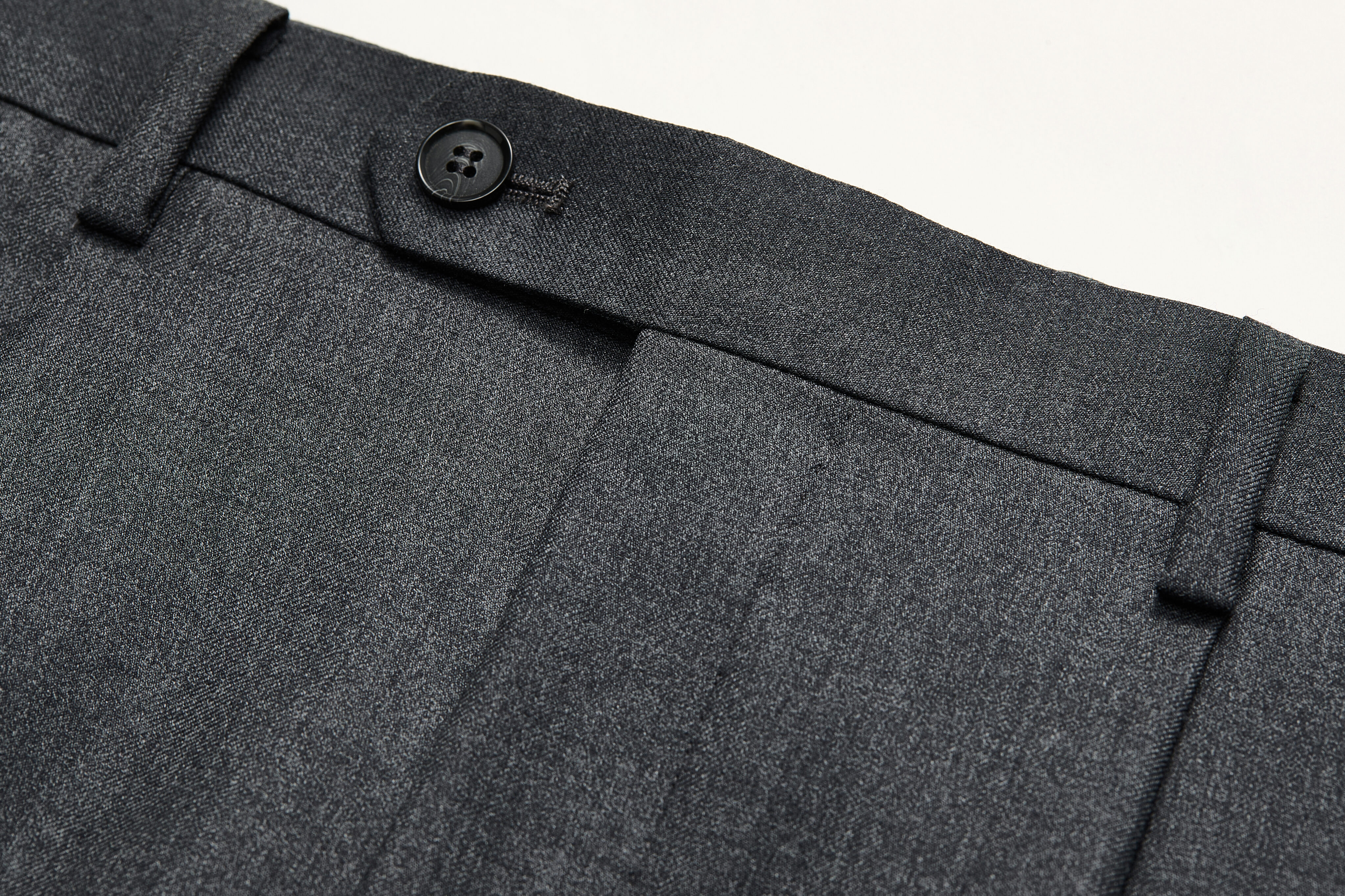 Belt loop detail on charcoal trousers.