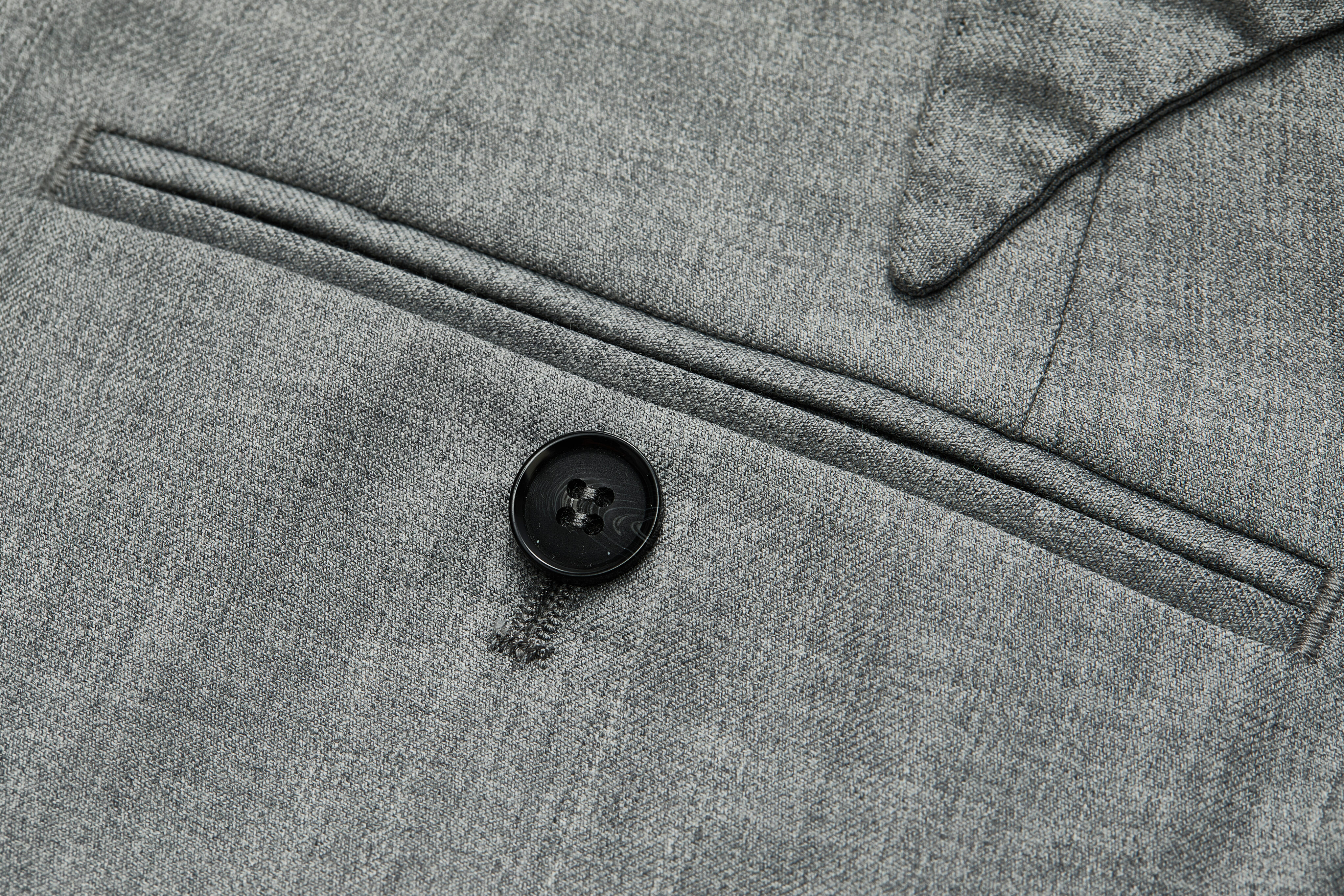 Jetted back pocket detail on grey trousers.