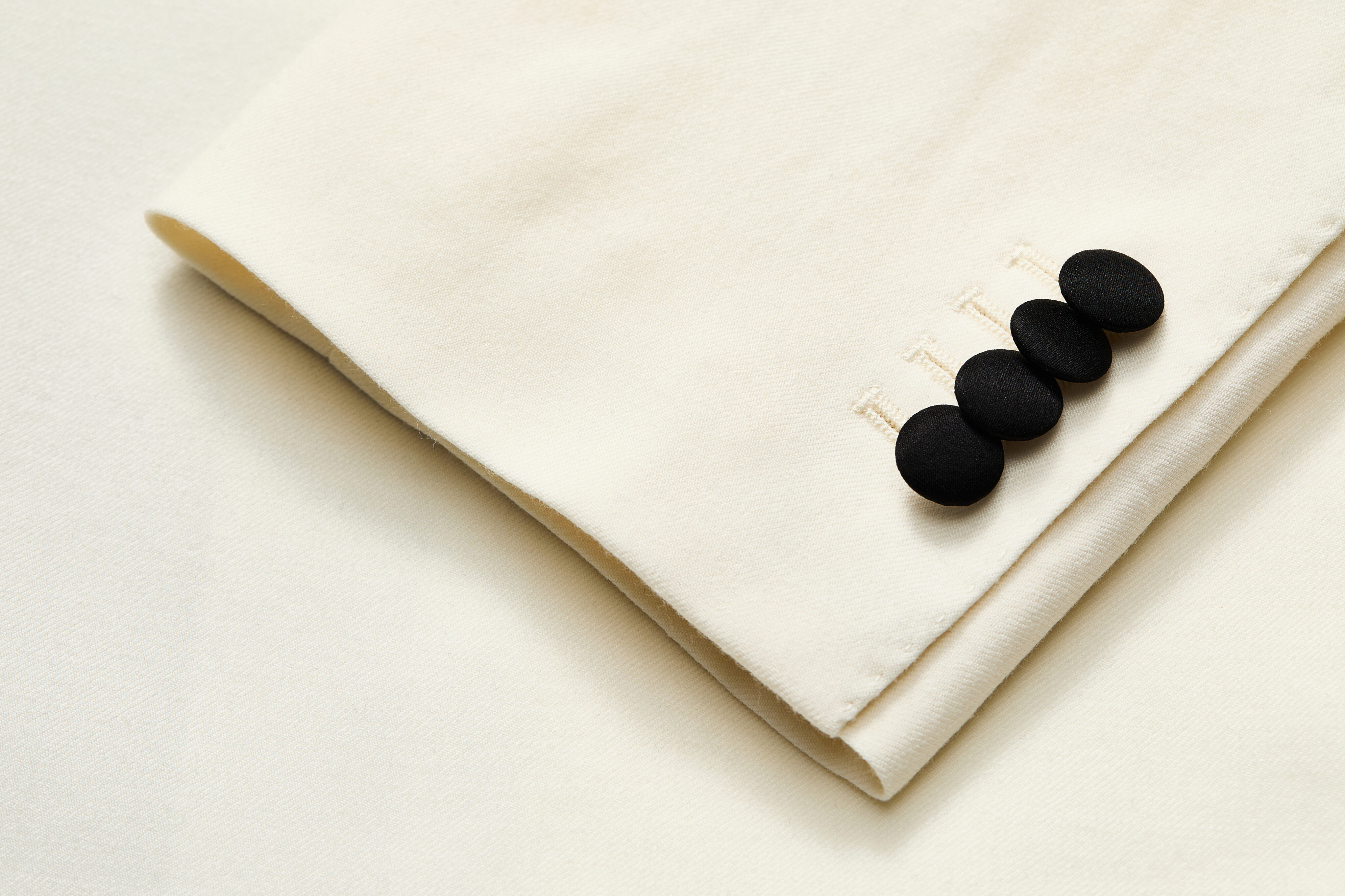 Covered button detail on ivory one-button dinner jacket.