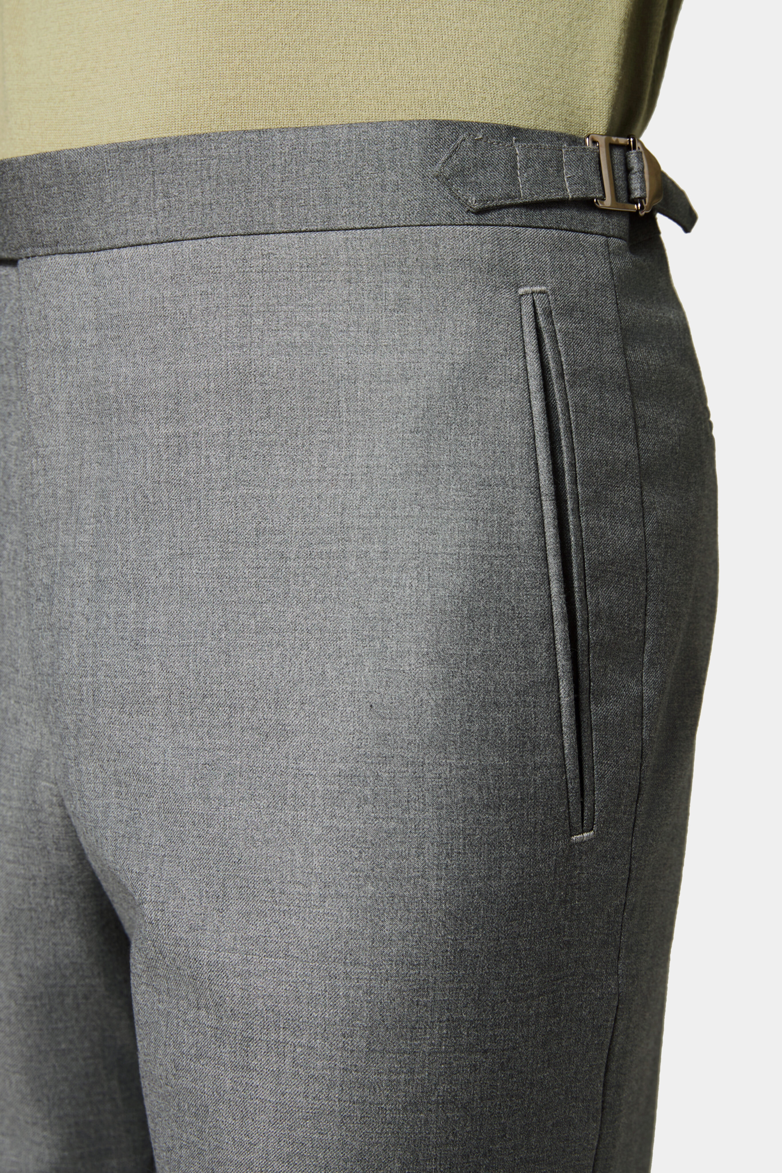 Double-jetted front pocket detail on light grey trousers.