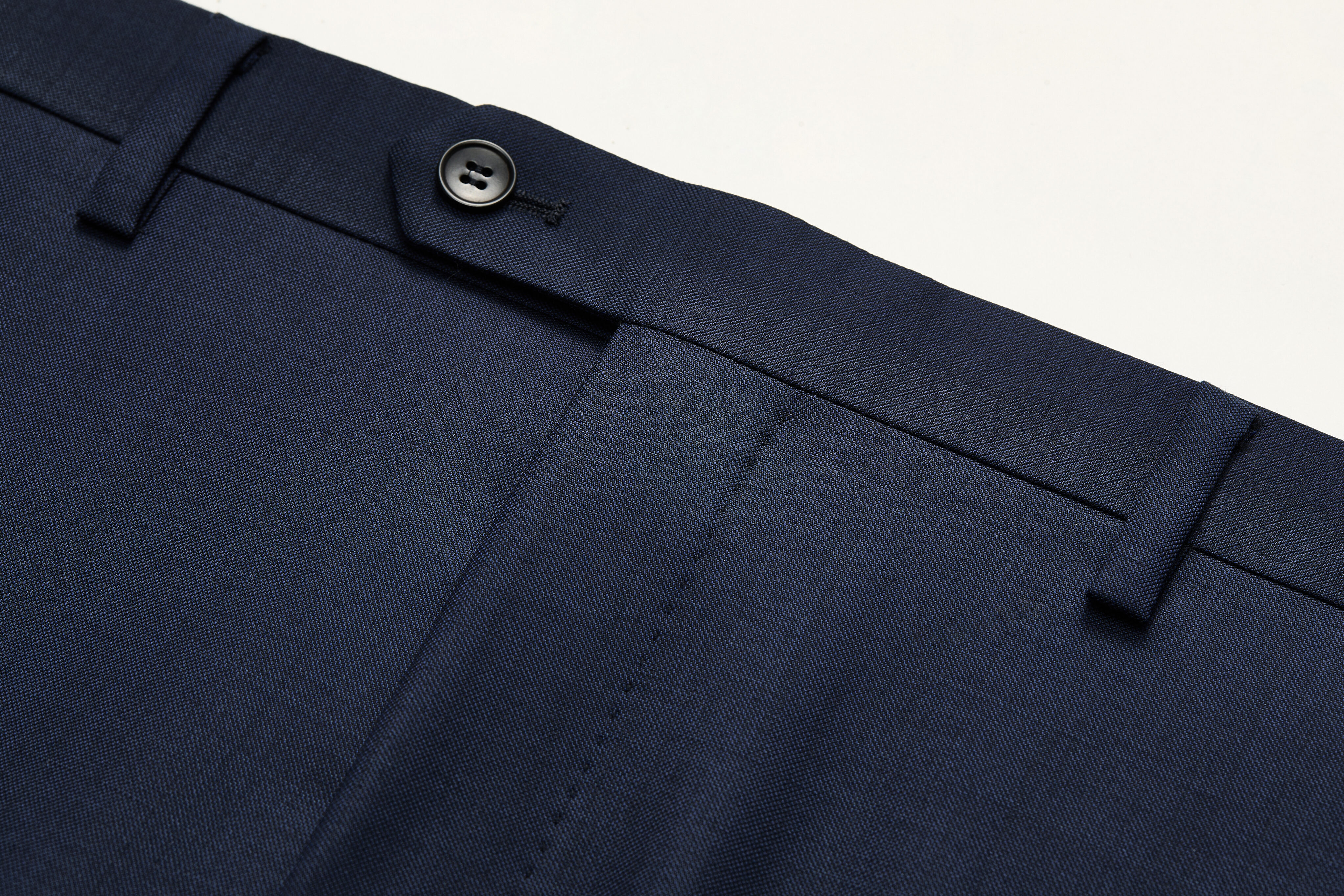Belt loop detail on navy wool trousers.