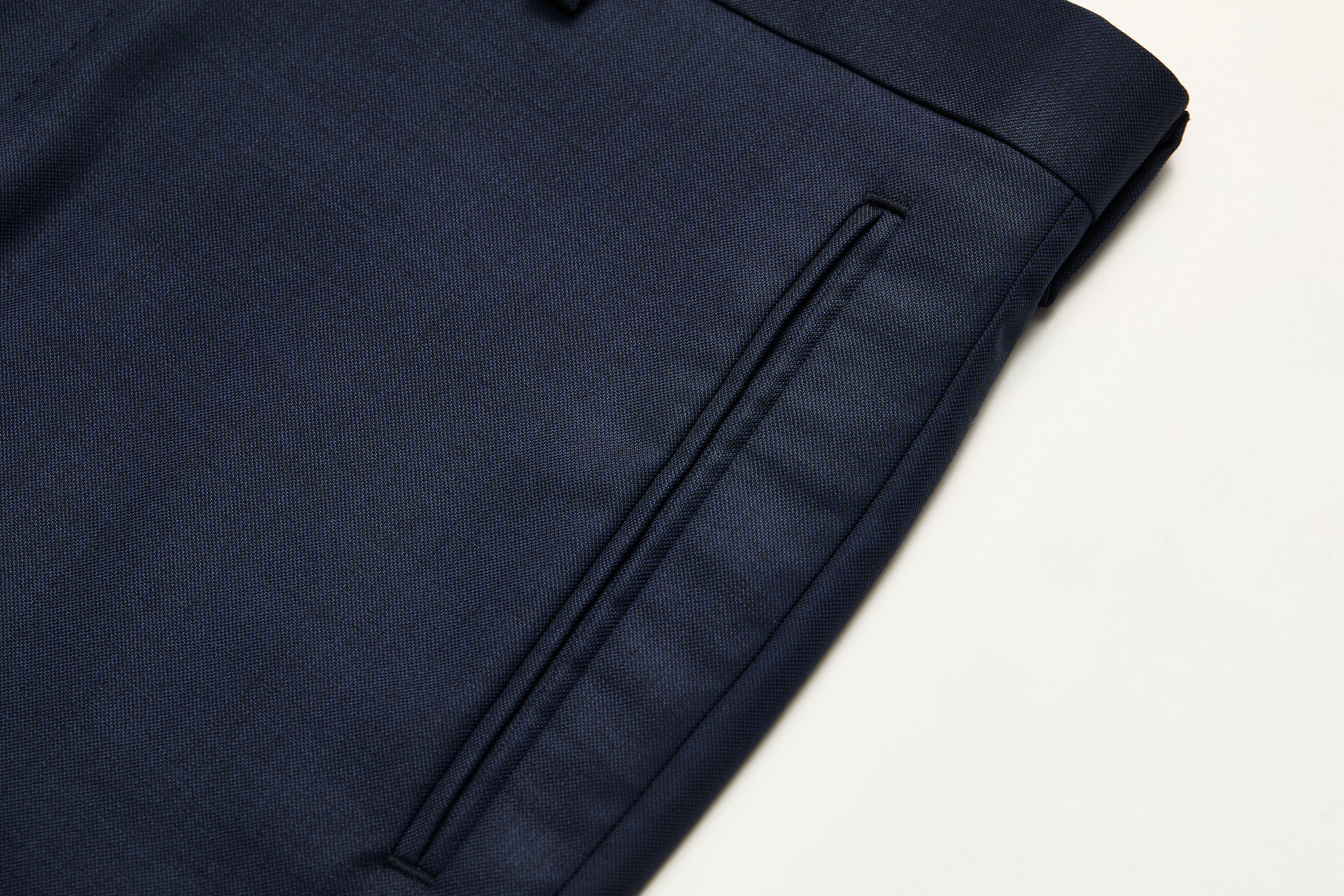 Jetted front pocket detail on navy trousers.
